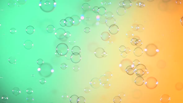Blue and Clear Soap Bubbles on Turquoise and Light Orange, Background, Slow Motion