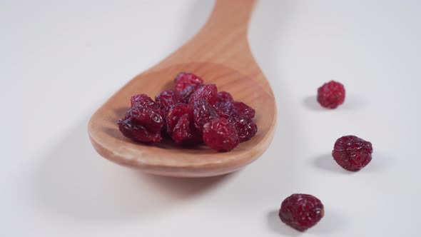 Red cranberries in a wooden spoon and scattered on a light gray table. 