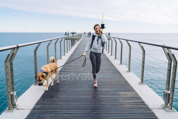 ith mongler dog using roaming connecting for making positive cellular conversation, happy female tourist in sportswear communicate via mobile app