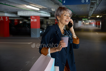 hrough parking of shopping mall. Senior lady sharing expression after successful purchases with low prices