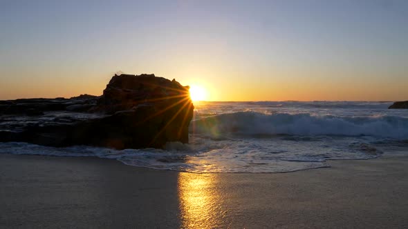 Walking the Sandy Beach During Sunset. Foamy Waves Are Rolling the Shore. The Sun Is Looking Out