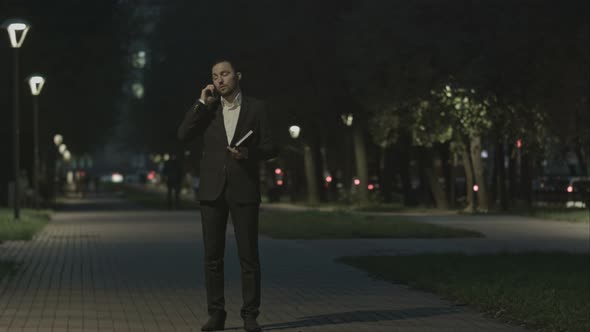 Businessman Talking By Phone While Walking in Park and Use Organizer