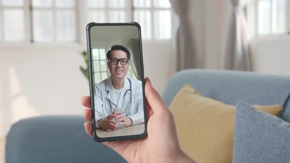 Close-Up Of A Person Video Conferencing With Male Doctor On Smartphone