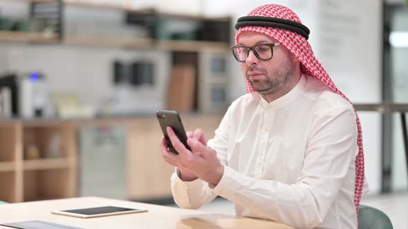 Attractive Young Arab Businessman Using Smartphone in Office