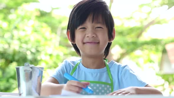 Cute Asian Child Drawing With Crayons On White Table