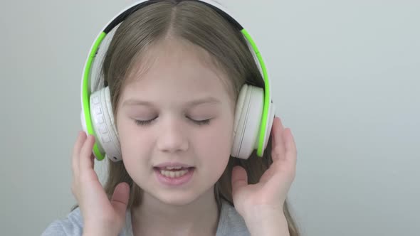Slow Motion Headshot of Girl in Big Headphones Listening to Music and Singing Song with Closed Eyes