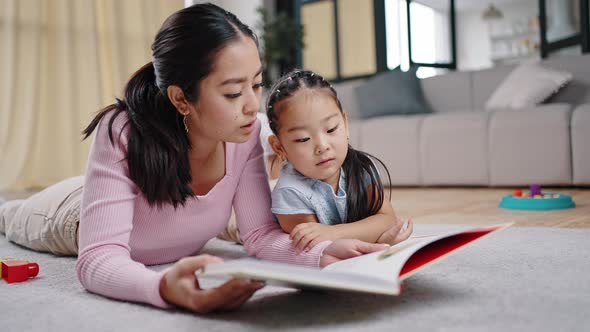 Mother Reads Story to Naughty Kid Lying Together on Floor