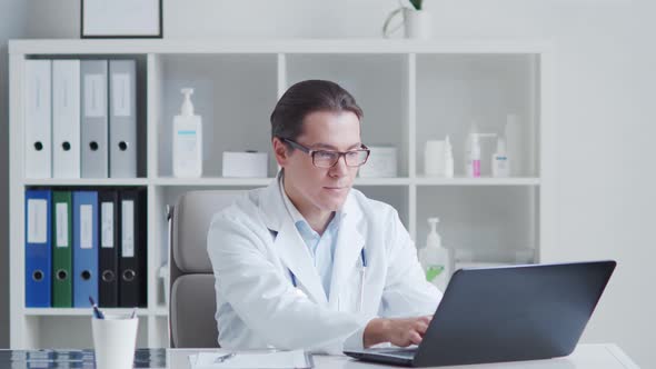 Professional medical doctor working in hospital office using computer technology.