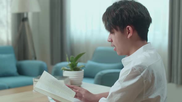 Asian Man Student Reading A Book While Studying At Home