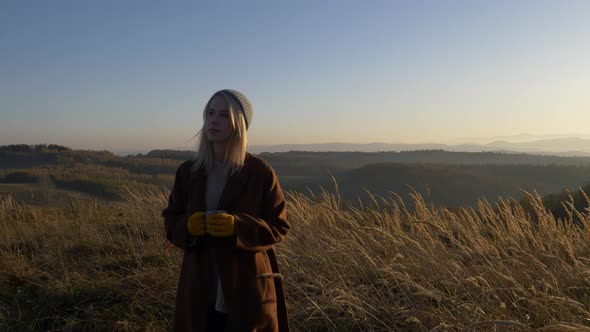 woman hold mug of tea in mountains Sudetes in November in sunset