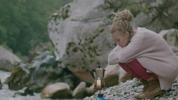 Travel Woman with dreadlocks Close making coffee with Mocha Pot in the forest on burner.