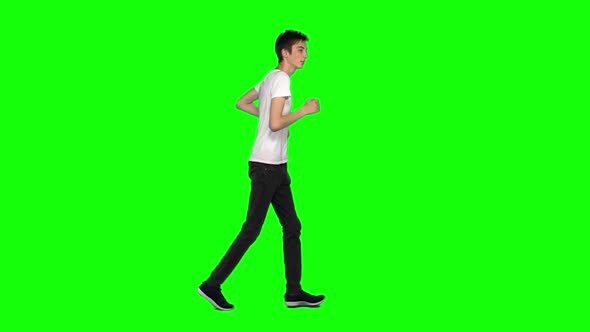 Tall Skinny Teen Guy Is Running on Green Screen Background. Chroma Key. Profile View. Slow Motion