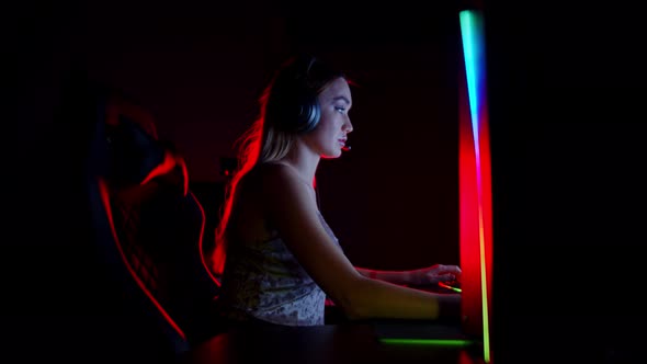 Tattooed Young Woman Sitting in Neon Gaming Club - Playing Game and Gets Excited