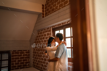 Asian young man and woman hugging each other in living room at home. 