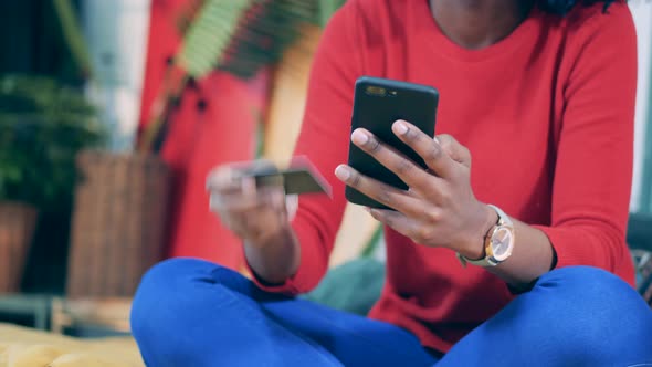 African Woman Is Holding a Phone and a Card During Online Shopping