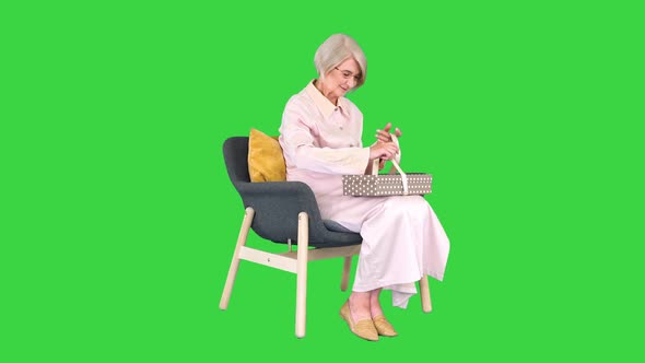 Happy Smiling Senior Woman Opening a Gift Box on a Green Screen Chroma Key