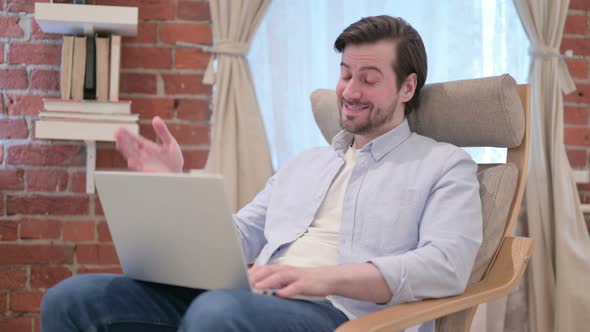 Casual Young Man Doing Video Call on Laptop on Sofa