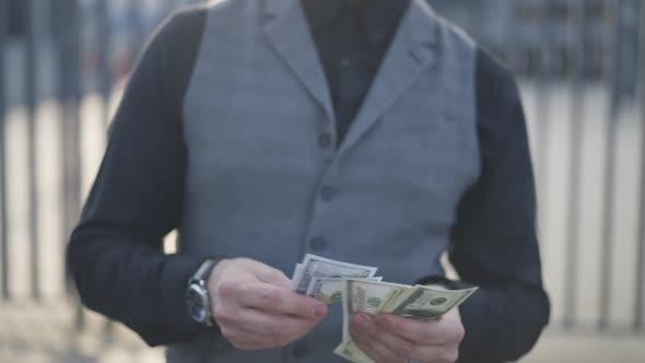 Unrecognizable Man Counting Cash Money in Urban City on Sunny Day