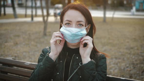 Young Woman in a Medical Mask for Protection From the Epidemic on the Street in the City. Concept