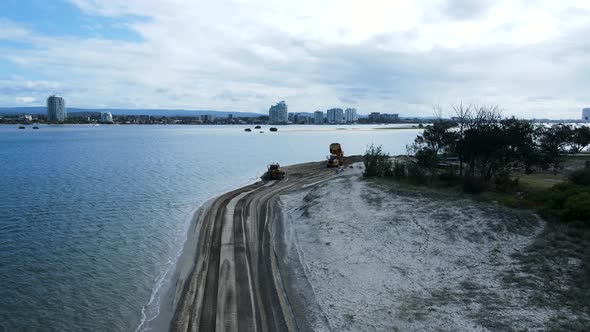 Revealing drone view of heavy machinery working on a beaching sand for a coastal erosion project. Pa