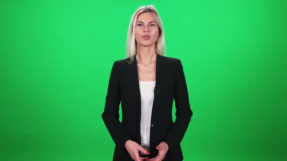 Woman Reporter in Suit Looks Into the Camera and Speaks in Lavalier Microphone Female on a Green