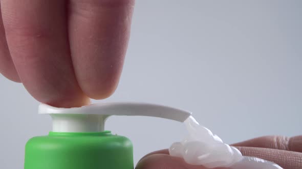 Hygienic liquid white soap is squeezed onto the hand. Sanitizer plastic container dispenser