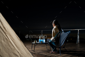 Woman go camping and cooking for dinner at night with her tent