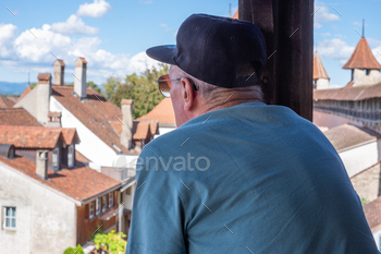 Back view of senior man looking away from the balcony of an ancient home enjoying travel destination