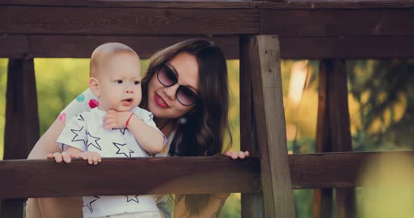 Pretty Baby with Her Mother Watching From the Bridge and Smiling