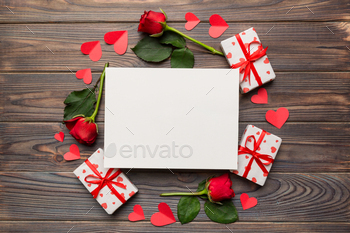 Frame made of rose, git box, heart and blank greeting card mockup on Colored background.