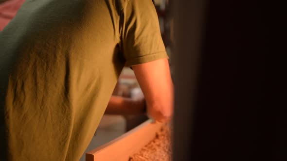 Young Handsome Male Woodoworker Planing Wood in His Workshop in Slow Motion