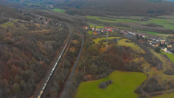 drone flight over a freight train transporting cargo through countryside