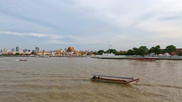 Small boats on Chao Phraya River and Wat Kalayanamit Woramahawihan Buddhist temple in Bangkok, Thail