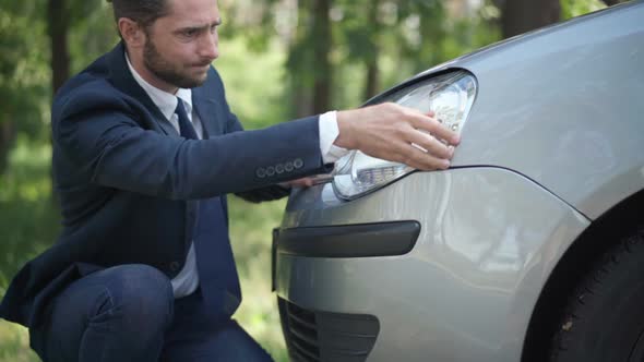 Portrait of Young Handsome Male Driver Pushing Car Headlight Fixing Damage