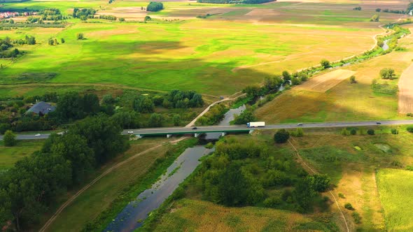 aerial drone shoot. Flying over a bridge green field in a rural landscape. Top view of trees in fore