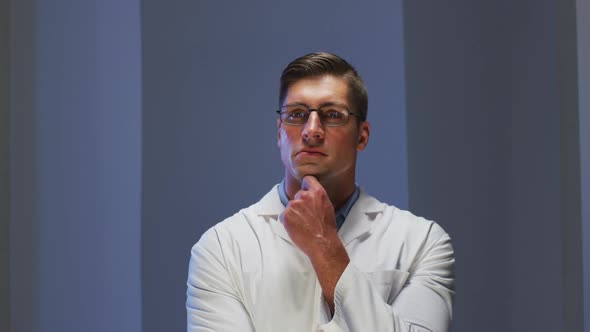 Caucasian male doctor wearing glasses looking at information using virtual digital interface