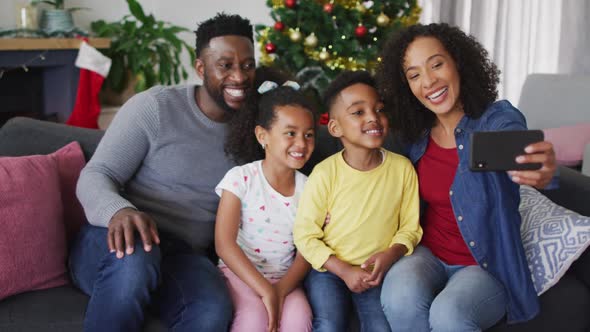 Smiling african american family taking selfie, christmas decorations in background