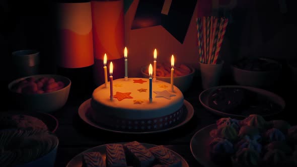 Birthday Cake On Table With Snack Foods In The Dark