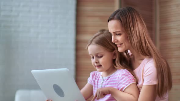 Caring Mother Hugging Little Daughter Talking Use Laptop Together