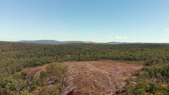 Aerial drone shot towards hikers in a clearing surrounded by green bushland