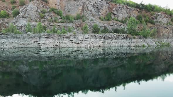 4K aerial video. Smooth takeoff above the water surface. Abandoned quarry