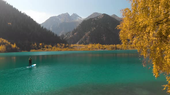 Man Is Paddling on Sup Board in the Mountain Lake