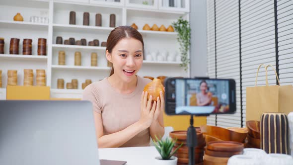 Asian business woman sell vase product online live streaming at home. Remote buying and purchase.