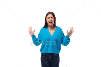 young charming brunette lady dressed in a blue V-neck sweater actively jests on a white background