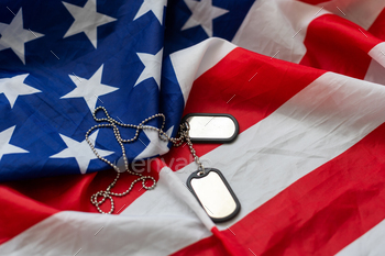 Dog tags and the flag of America. Focused on the dog tags.