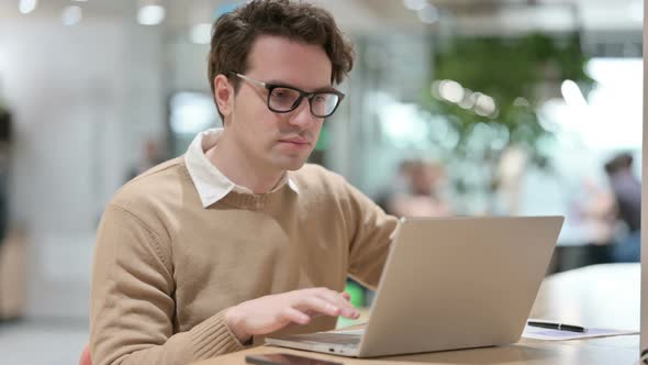 Young Male Designer with Laptop Looking at the Camera