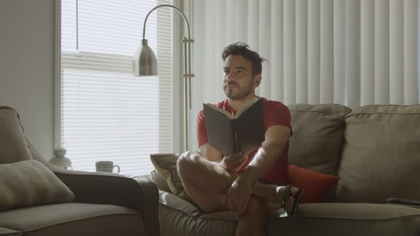 Slow Motion of Man Holding a Book As He Looks Up Thinking