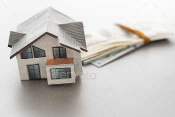 Wooden house model on background of US dollars banknotes. Housing market, purchase or rental of real