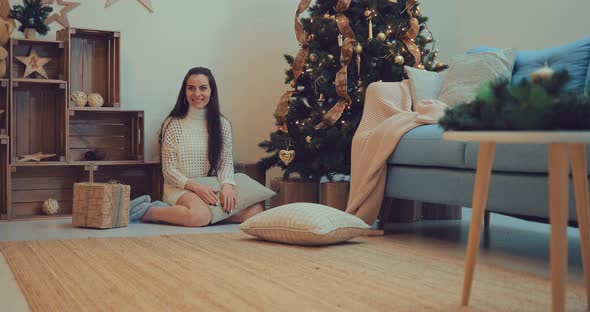 Happy Mother Plays with the Baby Near the New Year Tree