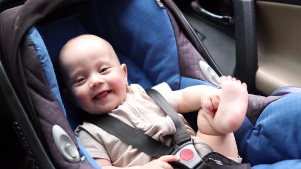 Happy Infant Baby Sitting in a Carseat Smiling